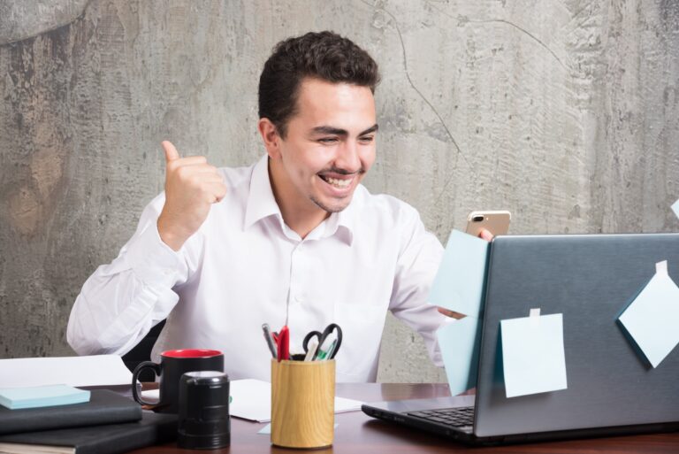 giovane uomo in ufficio davanti a pc felice