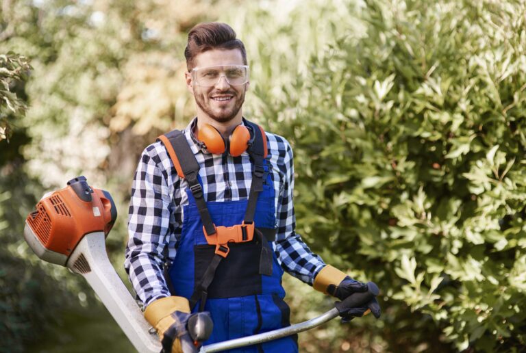 giardiniere che lavora in un parco per sistemare la siepe